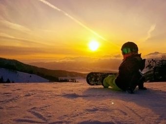 child snowboarder watching sunset